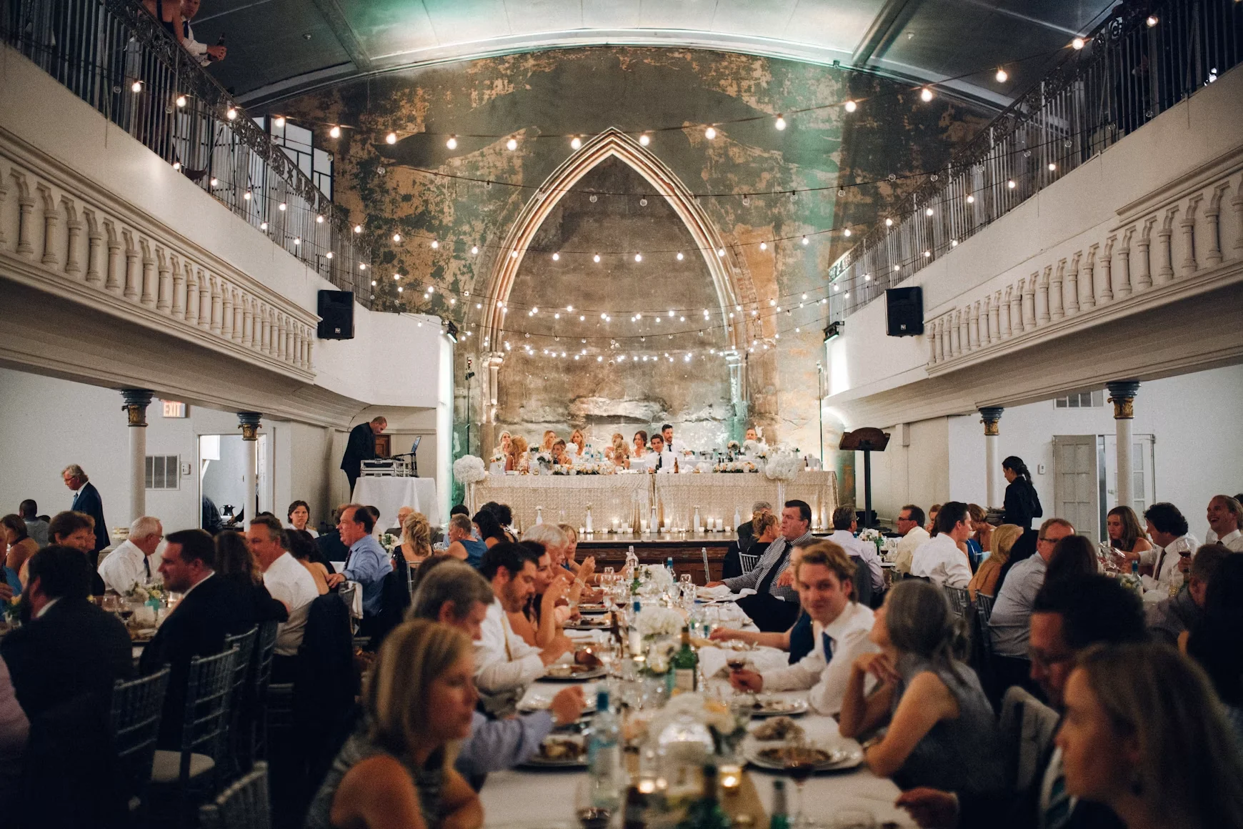 Wedding guests seated at long banquet tables in a grand reception hall