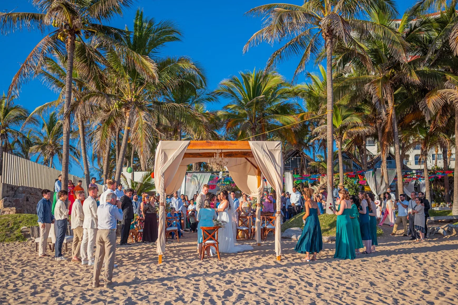 Guests gathered around a beach wedding ceremony canopy