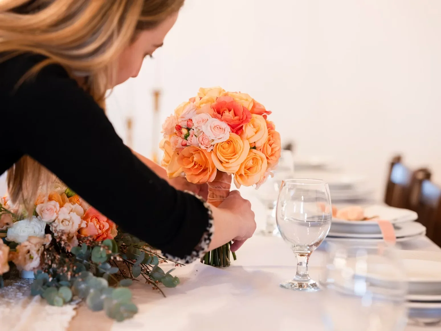 Florist arranging a rose bouquet on a styled reception table