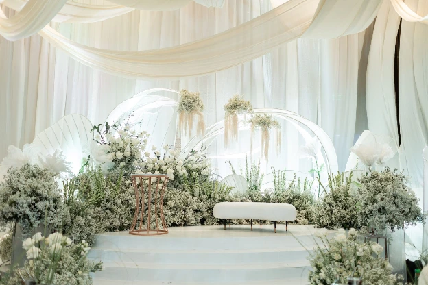 White ceremony stage with lush green and white wedding flowers by Flowers & Events by Teddy Manuel