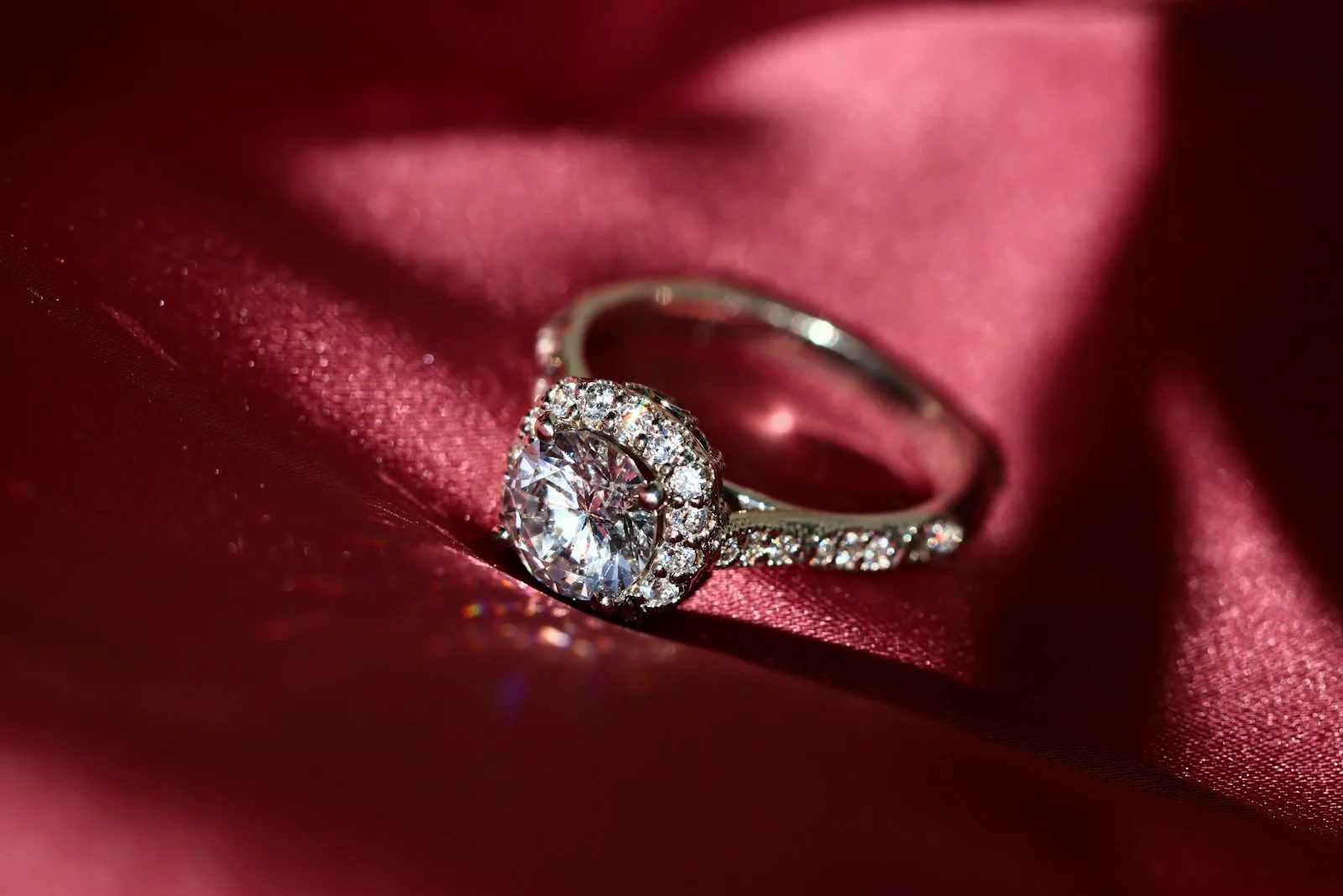 Diamond halo ring with a pave band on red silk