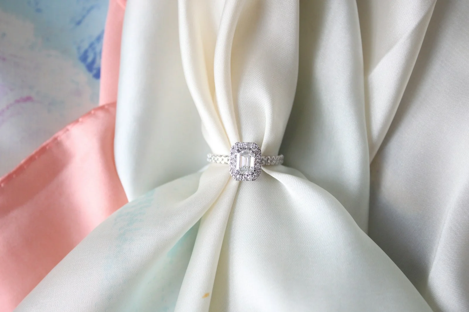 Emerald-cut diamond ring resting on white silk