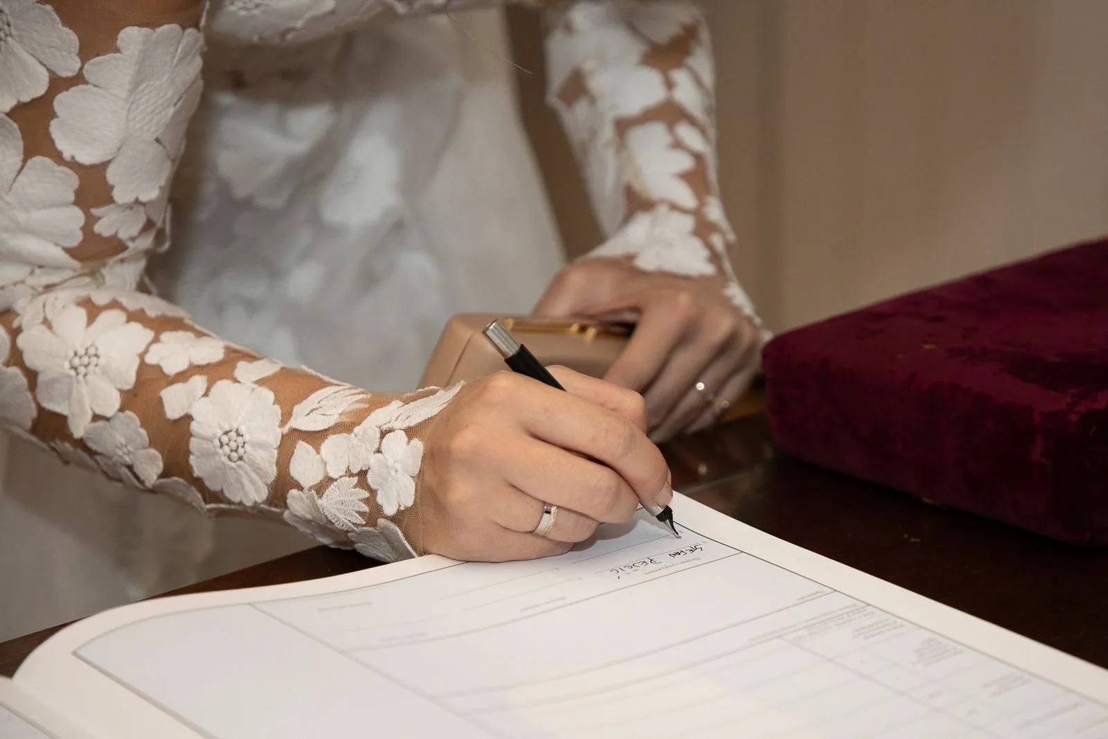 A bride in a lace gown signing the marriage register, for a New York City Hall or hotel ceremony | Wedded Wonderland