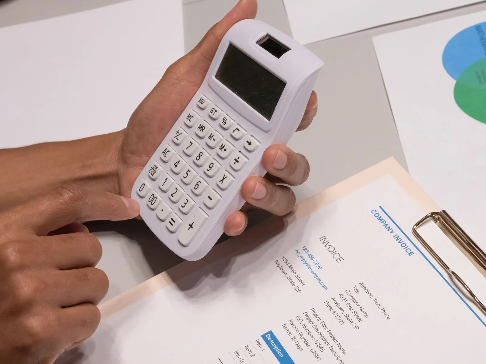 Hands working through an invoice on a calculator, for checking every extra venue charge | Wedded Wonderland