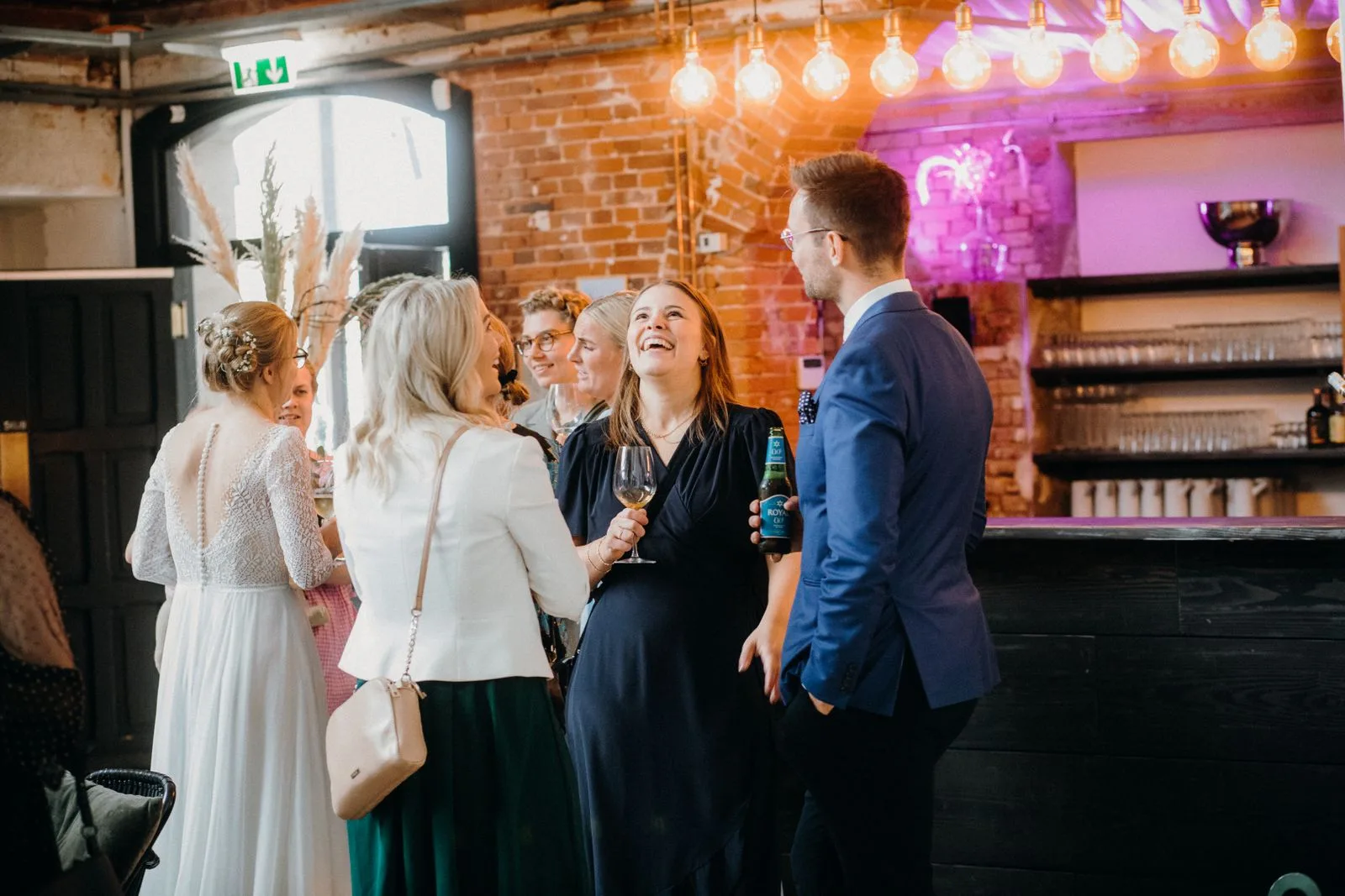 A bride and guests talking at a bar during a wedding after-party | Wedded Wonderland