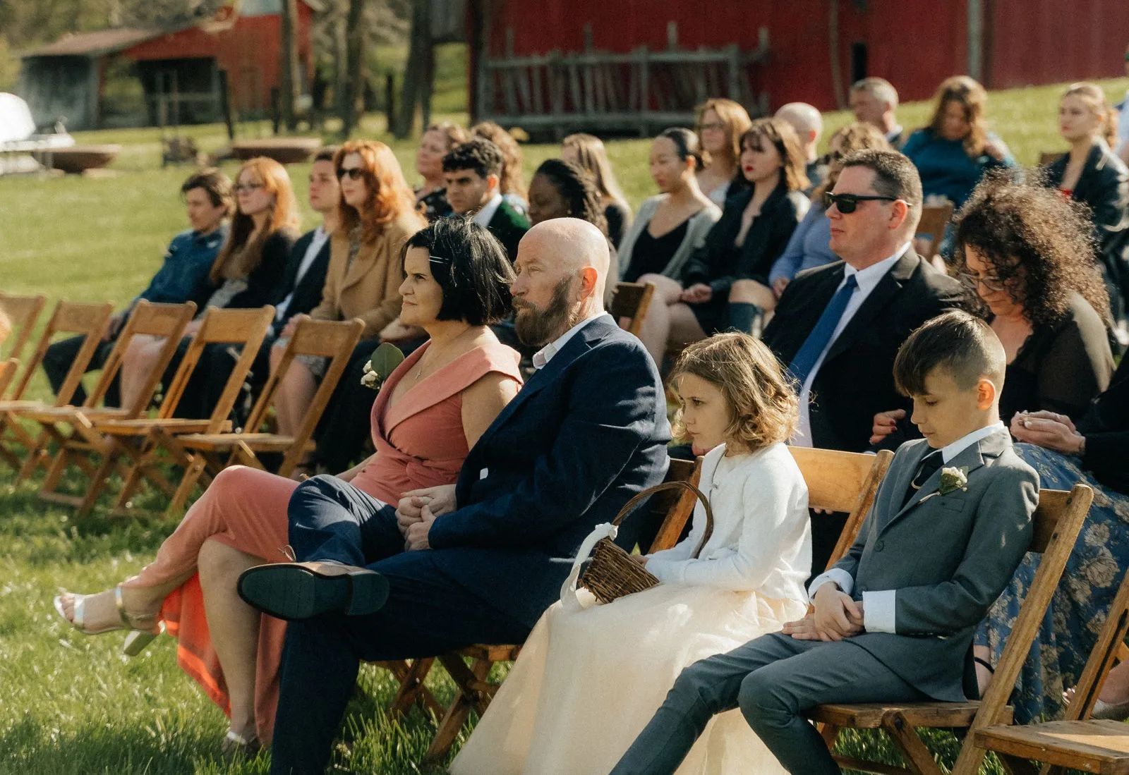 Guests on wooden chairs watching a phone free wedding ceremony outdoors, hands empty | Wedded Wonderland