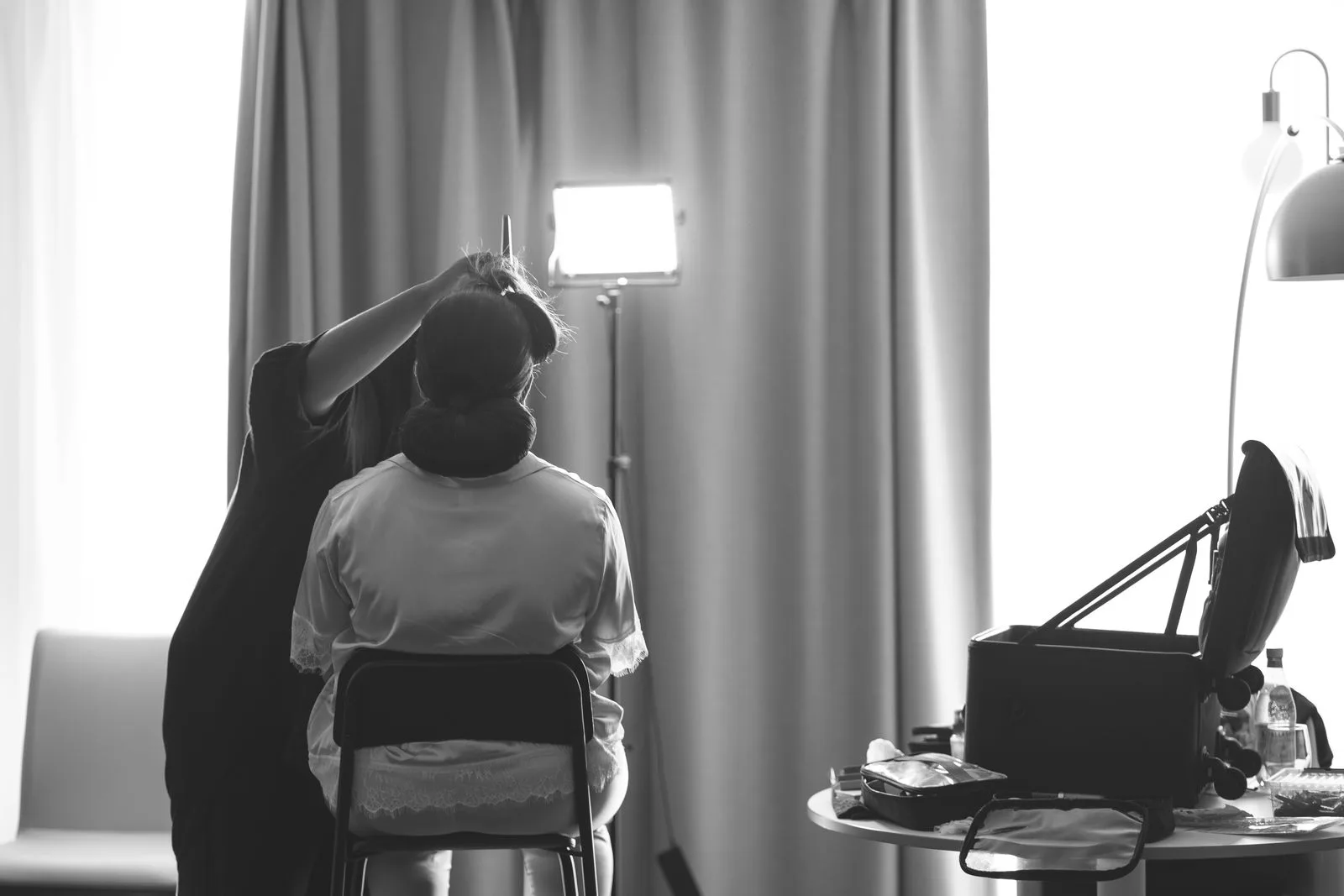 A bride in a robe seated for hair and makeup on her wedding morning, why vendors charge a bride tax | Wedded Wonderland